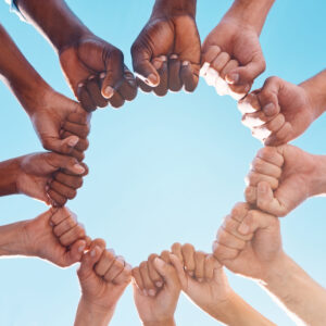 Fist hands, circle and diversity support human rights people, protest group and freedom of racism on blue sky background. Below solidarity, partnership and motivation of goals, trust or world justice Fist hands, circle and diversity support human rights people, protest group and freedom of racism on blue sky background. Below solidarity, partnership and motivation of goals, trust or world justice.